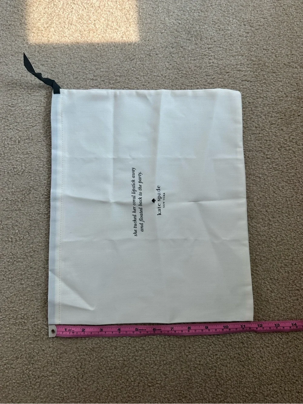 Kate Spade New York cream dust bag with black text and logo